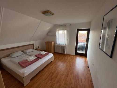 een slaapkamer met een bed en een houten vloer bij Szomszéd Ház in Keszthely