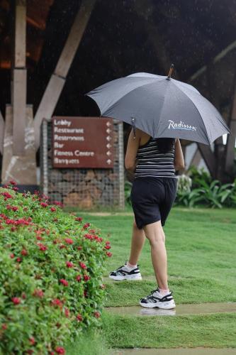 a person standing in the rain holding an umbrella at Radisson Resort Hatgad Saputara in Saputara
