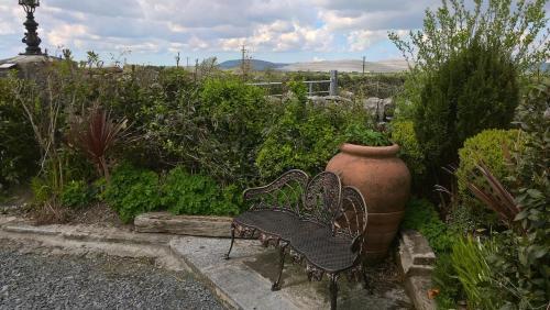 a bench and a large vase in a garden at The Burren Art Gallery built in 1798 in Tubber