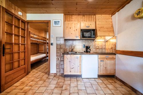 a kitchen with wooden cabinets and a refrigerator at La Flèche d'Or in Châtel