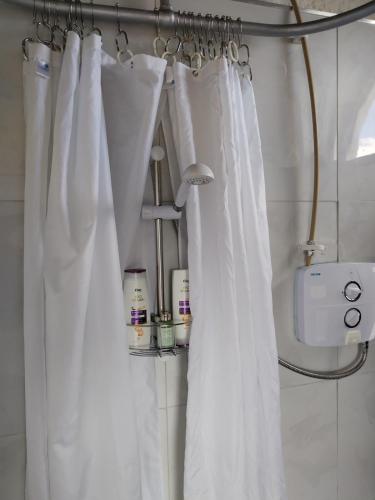 a bathroom with white shower curtains in a room at The Burren Art Gallery built in 1798 in Tubber