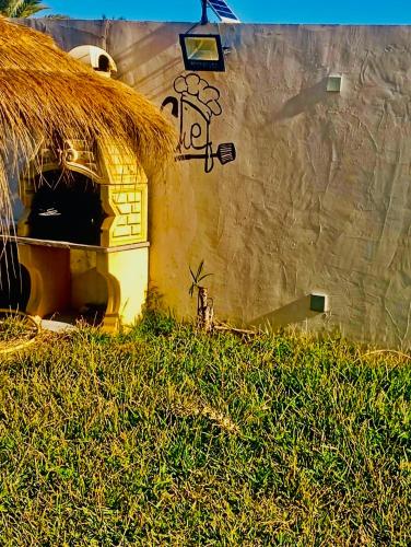 a building with a straw roof with graffiti on it at VILLA SOUNINE RAFRAF avec piscine in Bizerte