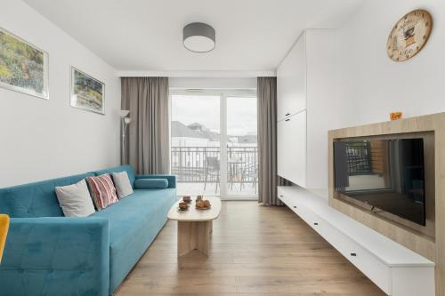 een woonkamer met een blauwe bank en een tv bij Sunny Apartments in Bel Mare Resort by Noclegi Renters in Międzyzdroje