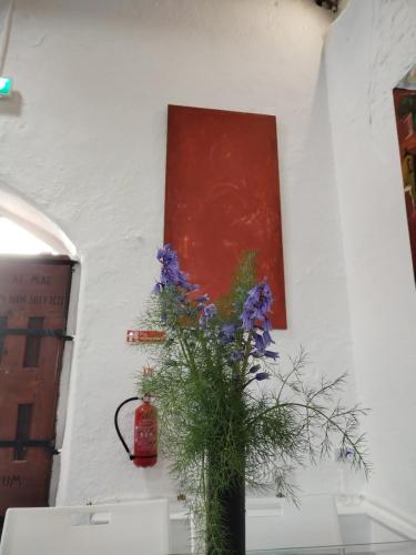 a vase with purple flowers on a wall with a painting at The Burren Art Gallery built in 1798 in Tubber