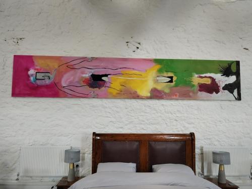 a painting hanging above a bed in a bedroom at The Burren Art Gallery built in 1798 in Tubber
