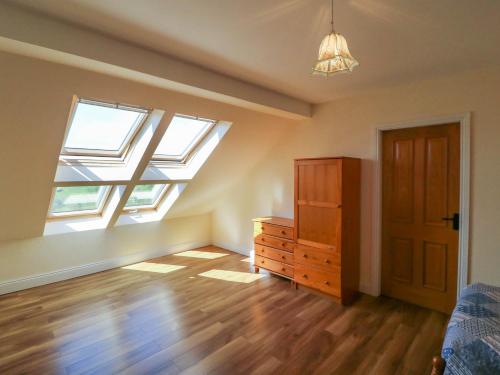 a bedroom with a bed and a dresser and windows at Curraha in Kenmare