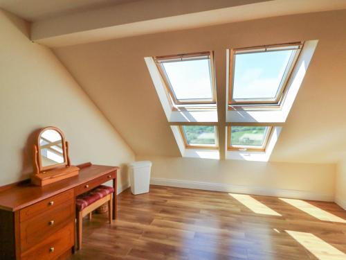 an attic room with a dresser and two windows at Curraha in Kenmare