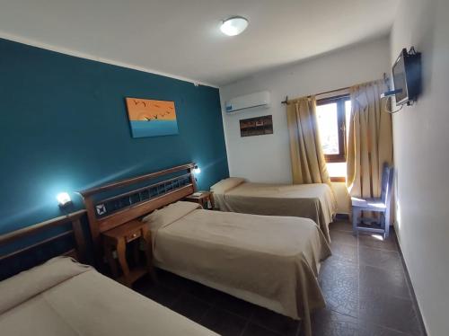 a room with three beds and a blue wall at Altos de Amaicha Posada Boutique in Amaicha del Valle
