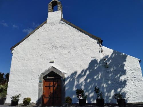 a white church with a brown door and a shadow at The Burren Art Gallery built in 1798 in Tubber