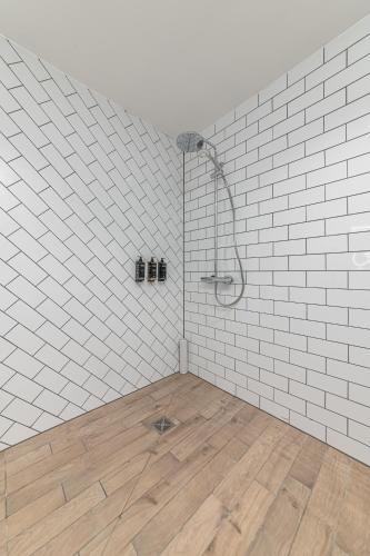 a shower in a white tiled bathroom with a wooden floor at Mercure Salisbury White Hart Hotel & Apartments in Salisbury
