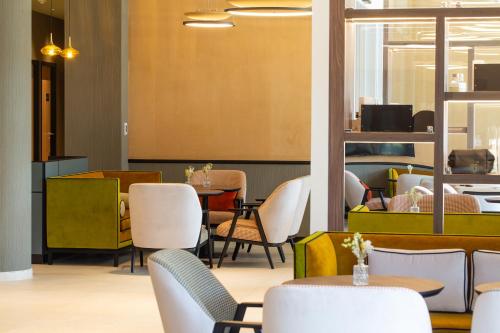 a restaurant with white chairs and tables and tablesktop at HÔTEL PANORAMA 360 Bourg en Bresse - Cœur de ville in Bourg-en-Bresse