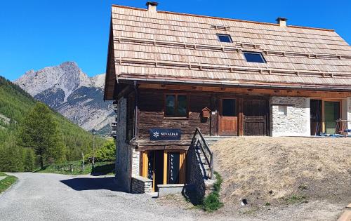 a building on a hill with mountains in the background at Chalet montagne 10 personnes in Ceillac