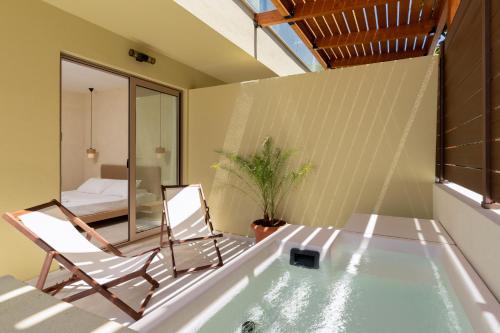 a room with a tub and a chair and a bed at Açai Plant Based Hotel in Rhodes Town