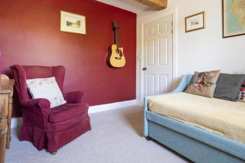 a bedroom with a chair and a guitar on the wall at Stamp Howe - Great Views with garden and pub nearby in Troutbeck