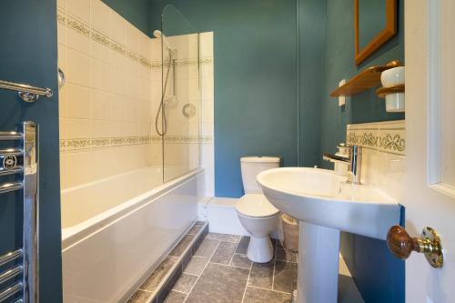 a bathroom with a sink and a toilet and a tub at Stamp Howe - Great Views with garden and pub nearby in Troutbeck