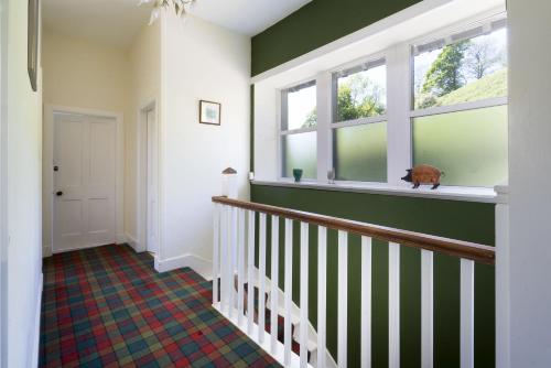 a hallway with green walls and a cat sitting on a window sill at Stamp Howe - Great Views with garden and pub nearby in Troutbeck