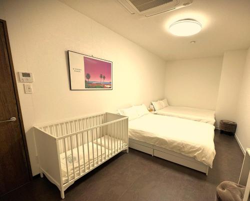 a room with two beds and a crib in it at Elena Premium Namba Stay in Osaka