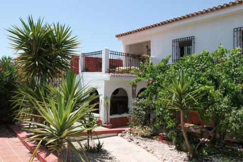 a white house with palm trees in front of it at Lovely 10-Bed Villa with Private Pool & Garden in Cacin