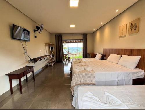 a bedroom with two beds and a desk and a television at CHALÉS VALE DO LAGO in Capitólio