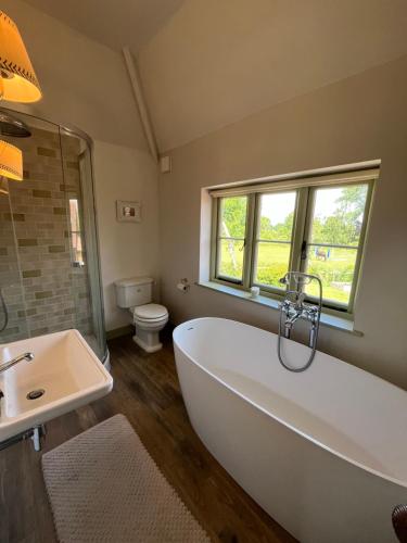 a bathroom with a tub and a sink and a toilet at Roost in Heyshott in Midhurst