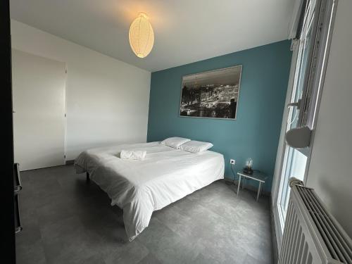 - une chambre avec un lit blanc et un mur bleu dans l'établissement Plantation FL - 4 Pers, Spacieux, Chaleureux, à Reims