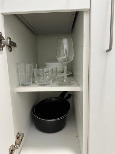 a shelf with glasses and a bowl and a wine glass at Train Station Aparthotel - Free Wifi, Free Parking in Scunthorpe