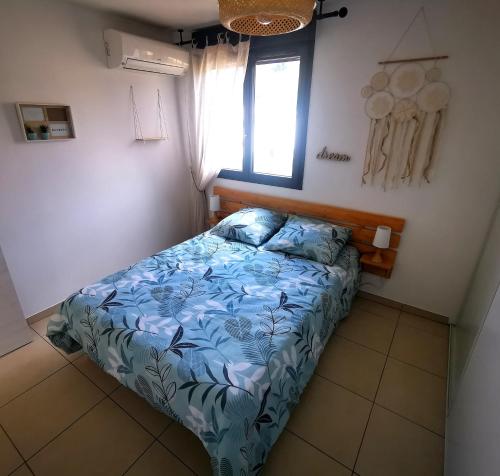 une chambre avec un lit avec une couette bleue et une fenêtre dans l'établissement Appartement T2 à Porto-Vecchio, à Porto-Vecchio