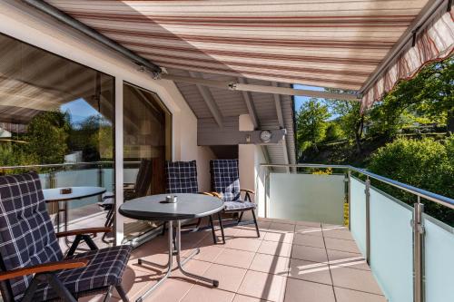 Un patio con mesas y sillas en un balcón. en Ferienwohnung Urban, en Bestwig