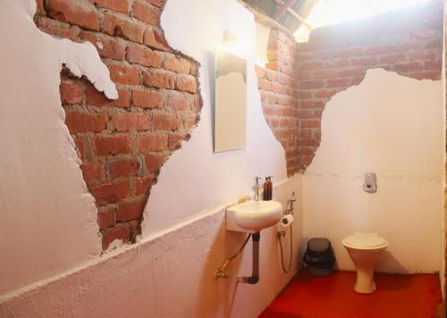 a bathroom with a brick wall and a sink at Neon Chameleon in Canacona
