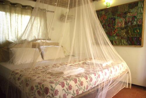 a bed with a net on top of it at Neon Chameleon in Canacona