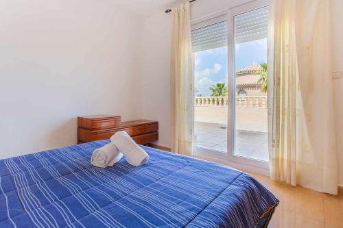 una camera con un letto blu e una grande finestra di Acogedor Chalet con piscina 2ª Línea del Mar Menor a Cartagena