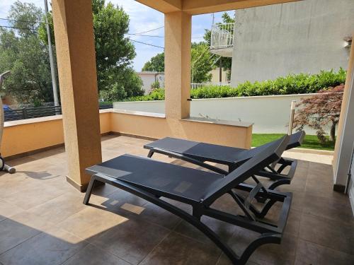a patio with two black lounge chairs on a porch at Residence Gordana in Selce