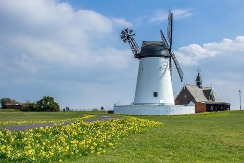 a white windmill in a field next to a building at The Bungalow and Studio Apartments in Lytham St Annes