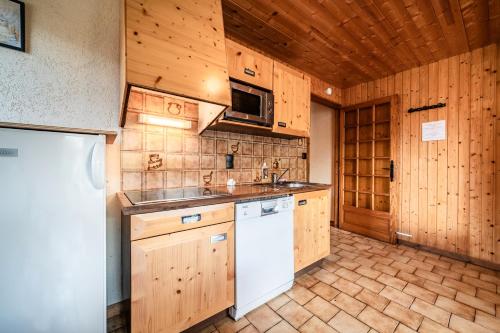 a kitchen with wooden cabinets and a white refrigerator at La Flèche d'Or in Châtel