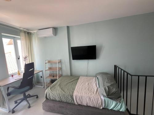 a bedroom with a bed and a desk and a television at Plomari Grey house Casa Peppe in Plomarion