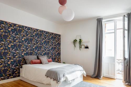 une chambre avec un lit avec un mur d'accent floral dans l'établissement Maison de charme avec piscine, à Dax