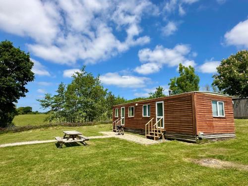 a wooden cabin in a field with a picnic table at Simene cabin in Bridport
