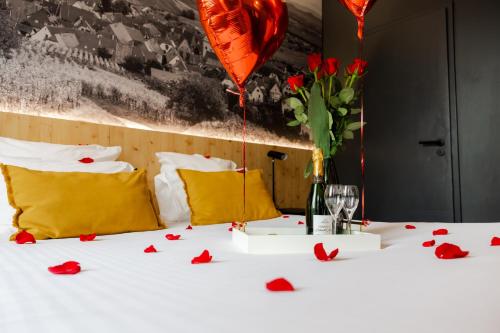 a table with red roses and a vase and balloons at L' Hôtel & Spa Ribeauville- Haut-Koenigsbourg in Ribeauvillé