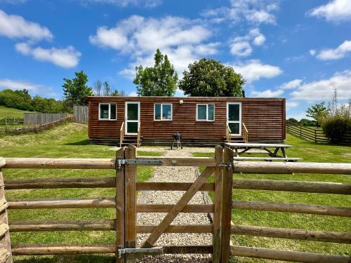 a log cabin in a field with a fence at Simene cabin in Bridport