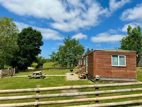 a wooden cabin in a field with a fence at Simene cabin in Bridport
