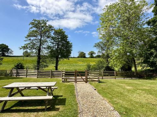 a picnic table in a field next to a fence at Simene cabin in Bridport