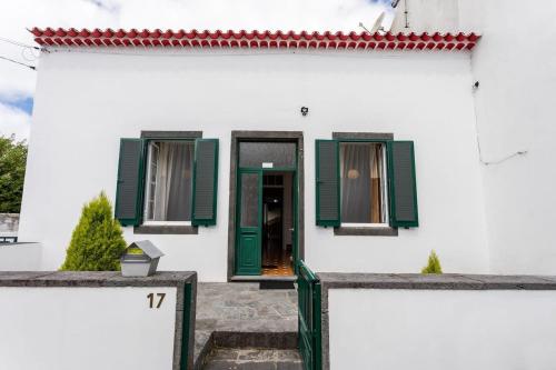 a white house with green shutters and a door at GuestReady - Furnas Nest in Furnas