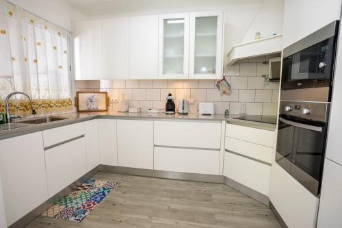a kitchen with white cabinets and a wooden floor at GuestReady - Furnas Nest in Furnas