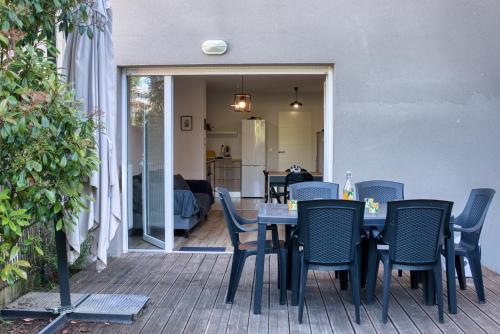 Une table à manger et des chaises sont disponibles sur la terrasse. dans l'établissement Agréable duplex avec jardin et terrasse, à La Teste-de-Buch