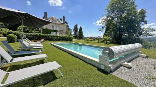 - une piscine avec 2 chaises longues et un parasol dans l'établissement Le petit chateau, à Vicq-sur-Breuilh