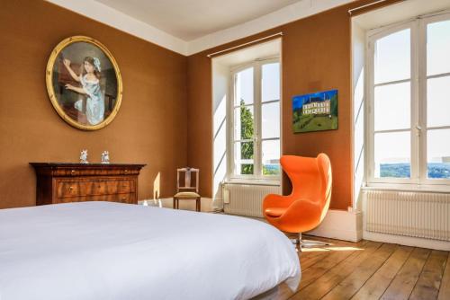a bedroom with a bed and a chair and windows at Le petit chateau in Vicq-sur-Breuilh