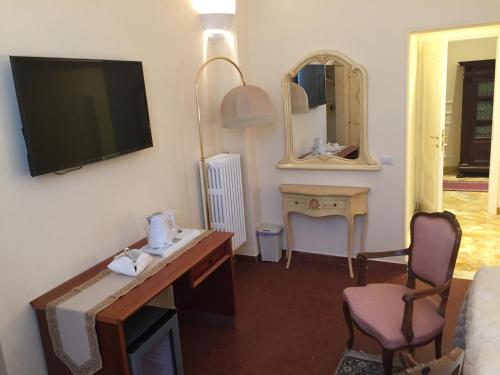 a hotel room with a tv and a desk and chairs at Casalbergo in Siena