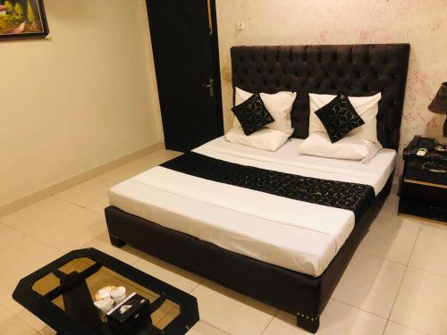 a bedroom with a large bed with a black headboard at Hotel Tulip Inn in Lahore