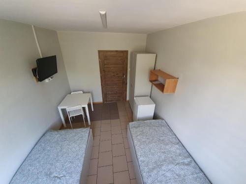 a small room with two beds and a tv at Kwatery pracownicze in Łódź