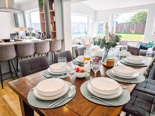 ein Esszimmer mit einem Holztisch mit Tellern und Gläsern in der Unterkunft Luxury Sea View Retreat with Hot Tub Sleeps 8 in Dover